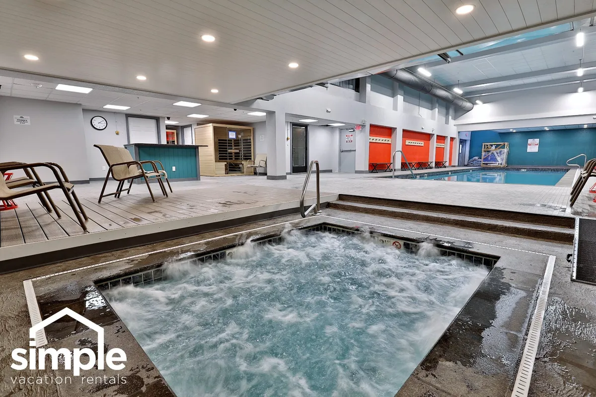 An inviting indoor space featuring a hot tub, swimming pool, lounge chairs, a clock on the wall, and a welcoming reception area. Several guests are seen relaxing in the hot tub, swimming, and enjoying each other's company in a bright, tranquil environment.