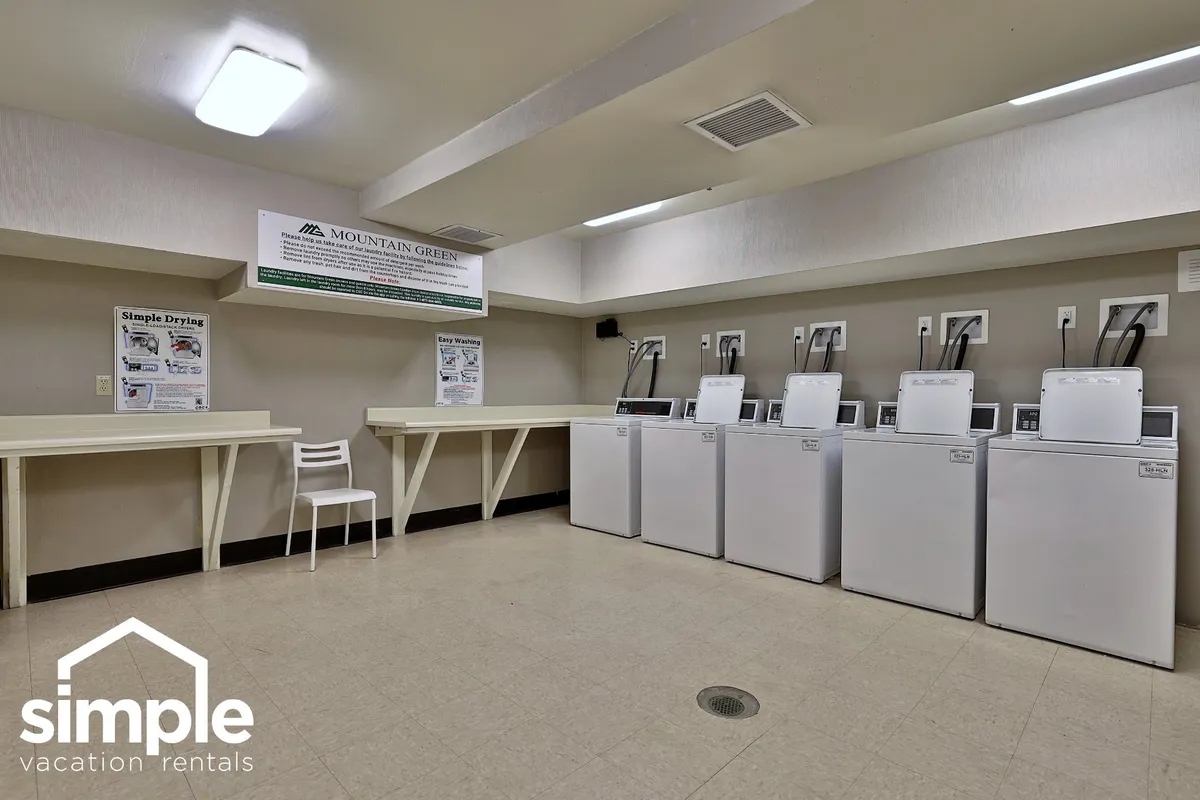 A practical, user-friendly laundry room with washing machines, dryers, informational posters, and a simple white chair. The mood is straightforward and clean, emphasizing convenience for guests.
